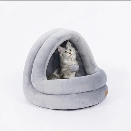 Un gato sentado dentro de una cama redonda y lujosa para gatos. La cama para gatos parece estar diseñada para proporcionar un espacio acogedor y confortable para que el gato descanse o duerma. El gato parece relajado y mira directamente a la cámara.