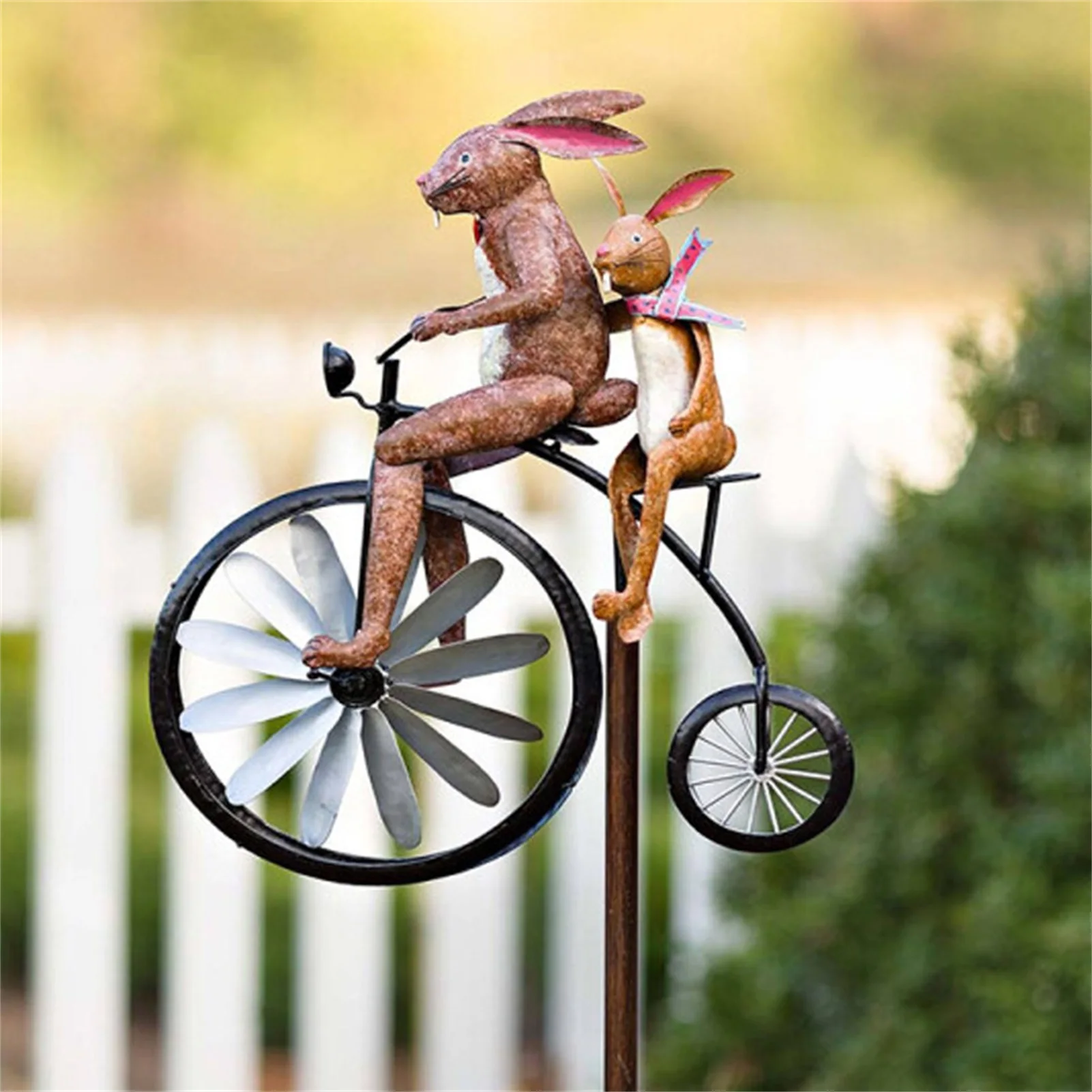 Una estatua de conejos montando una bicicleta con una estatua de gato en la parte posterior