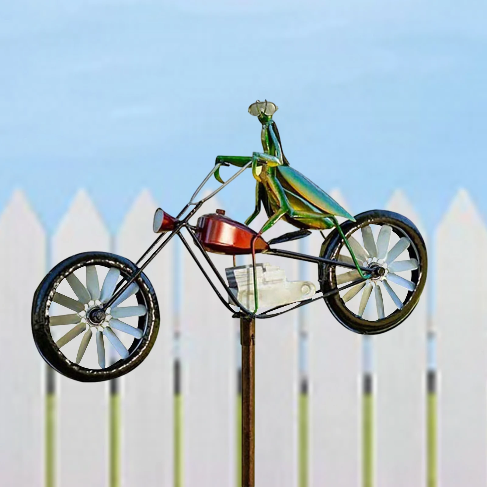 Una motocicleta de juguete está en un poste frente a una cerca blanca