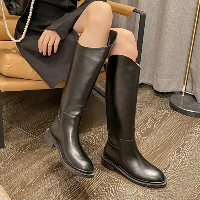 Una mujer con botas negras y un vestido