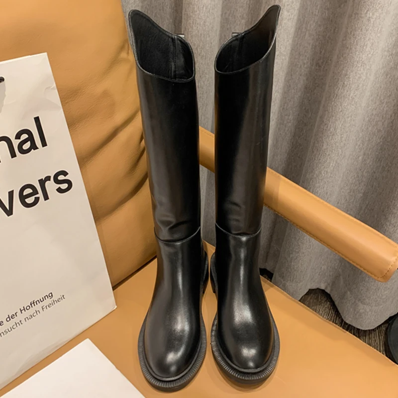 Un par de botas negras se sientan en una silla al lado de una bolsa