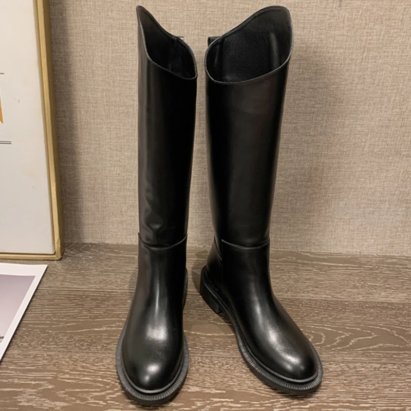 Un par de botas negras están en un piso de madera.