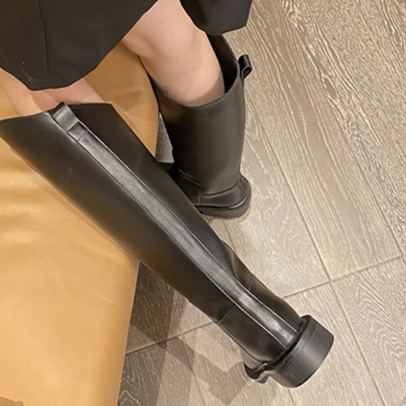 Una mujer con botas negras y un vestido