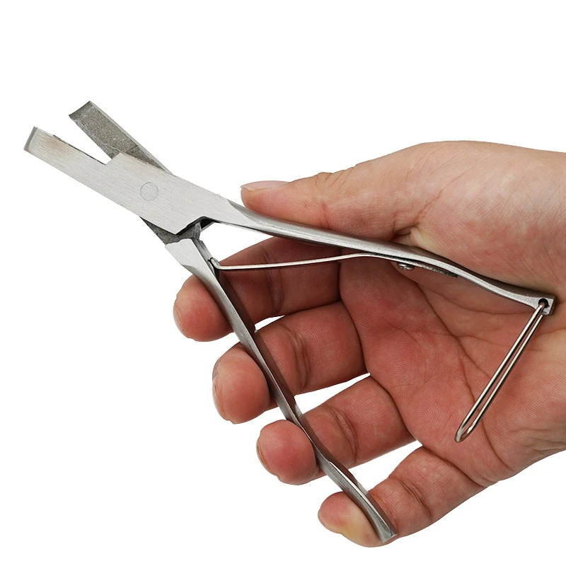 Alicates de acero inoxidable en acción marcando una oreja en forma de U