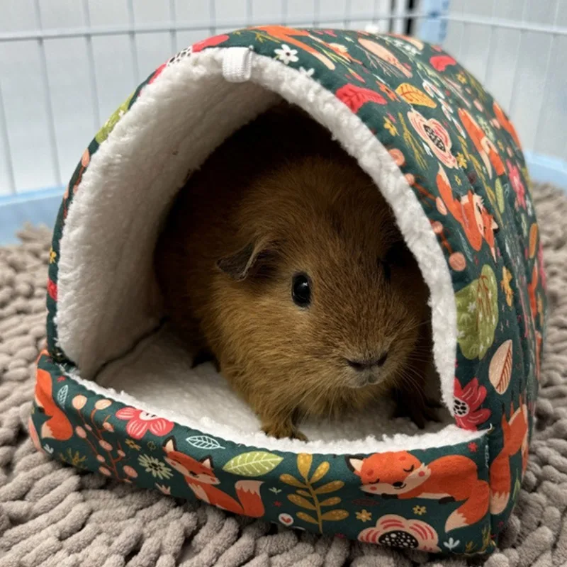 Un animal pequeño posiblemente un hámster, está sentado en una cama con una manta blanca y verde