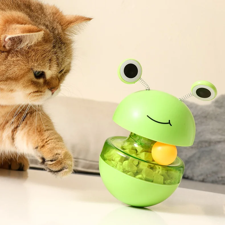 Gato jugando concentrado con el dispensador de rana