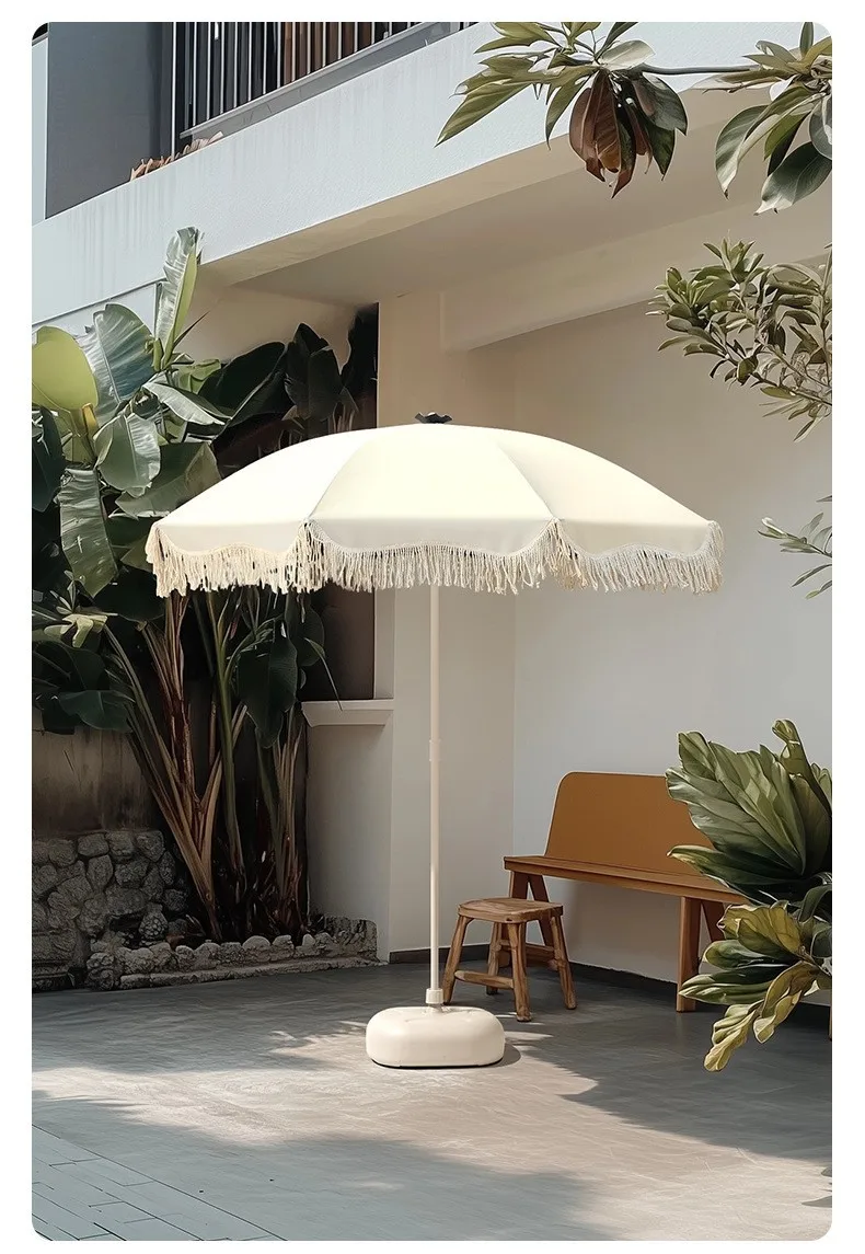Sombrilla grande con borlas en jardín exterior