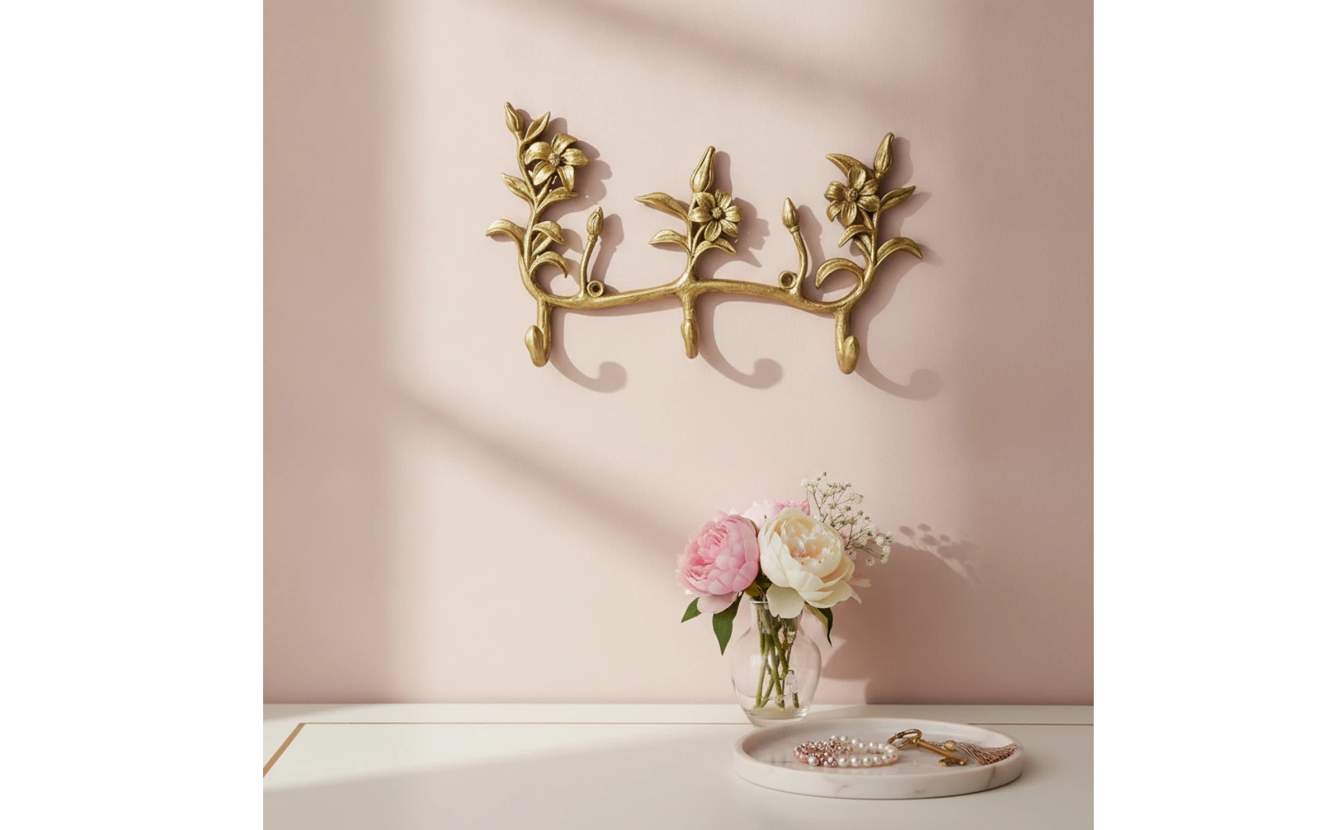 Vista general del perchero floral dorado montado en pared clara con accesorios colgados