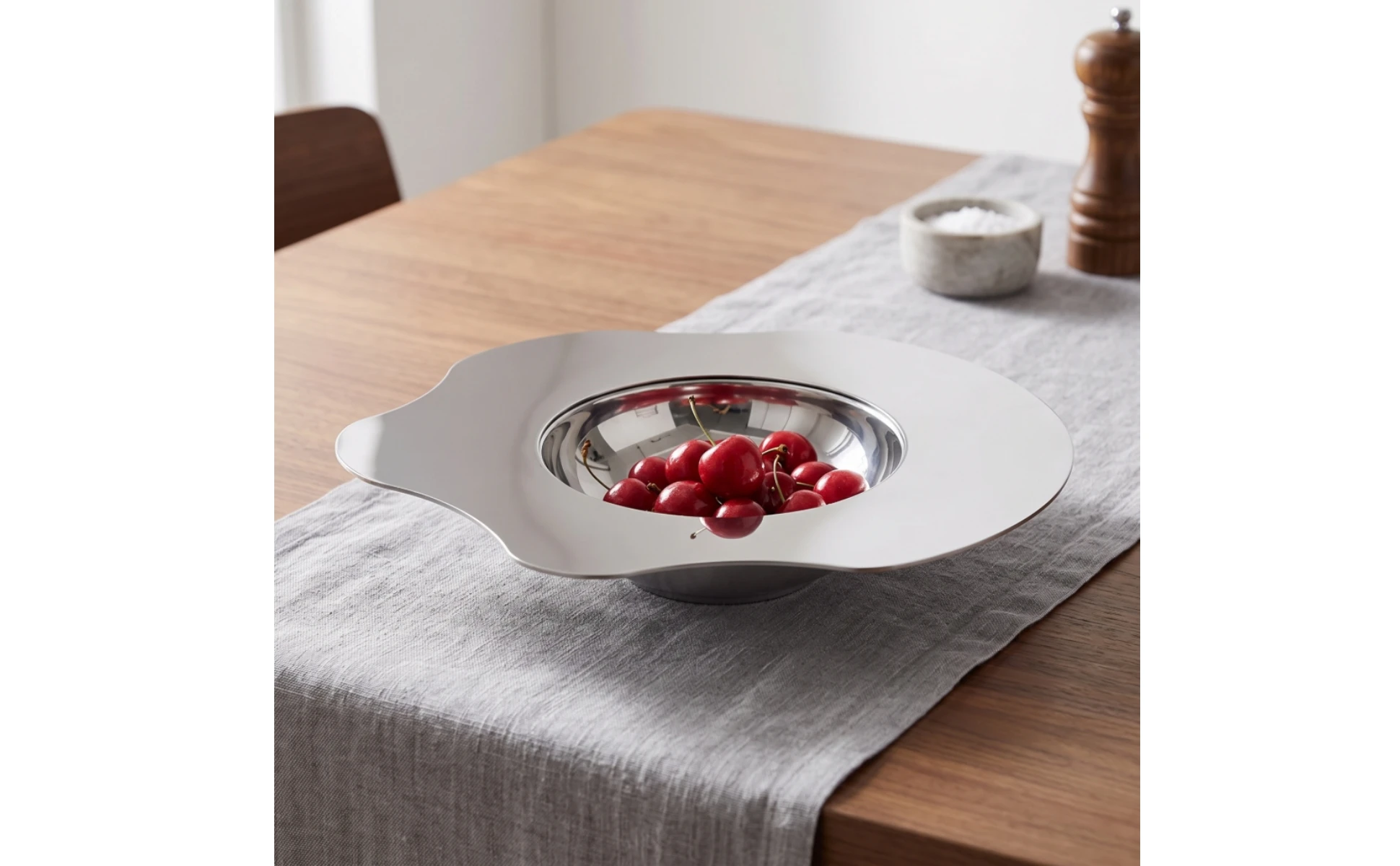 Bandeja de acero inoxidable con diseño floral minimalista sobre mesa de madera