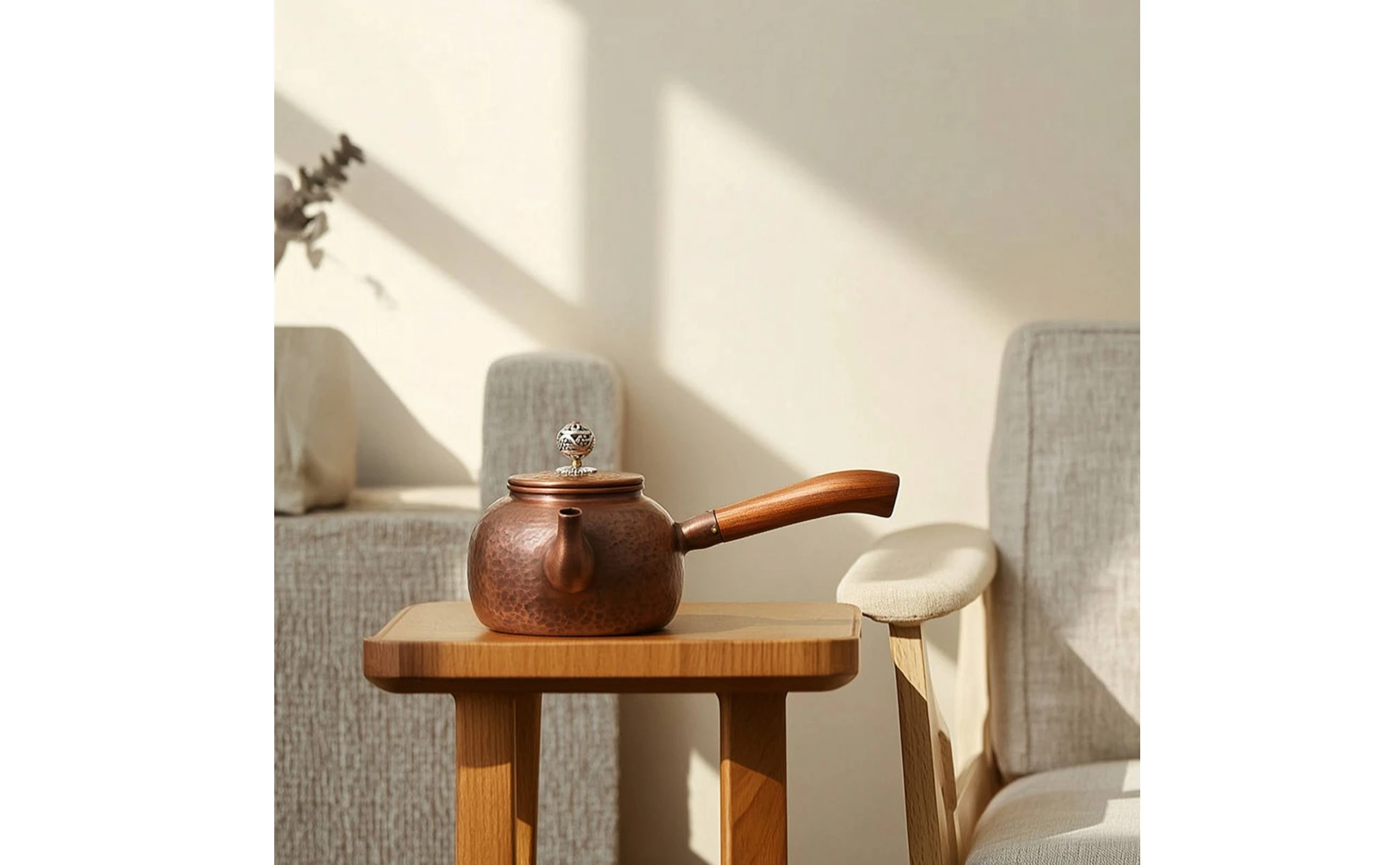Detalle del asa de madera y la textura martillada de la tetera