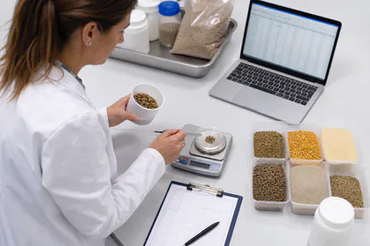 Profesional formulando una dieta animal con ingredientes pesados y datos nutricionales.